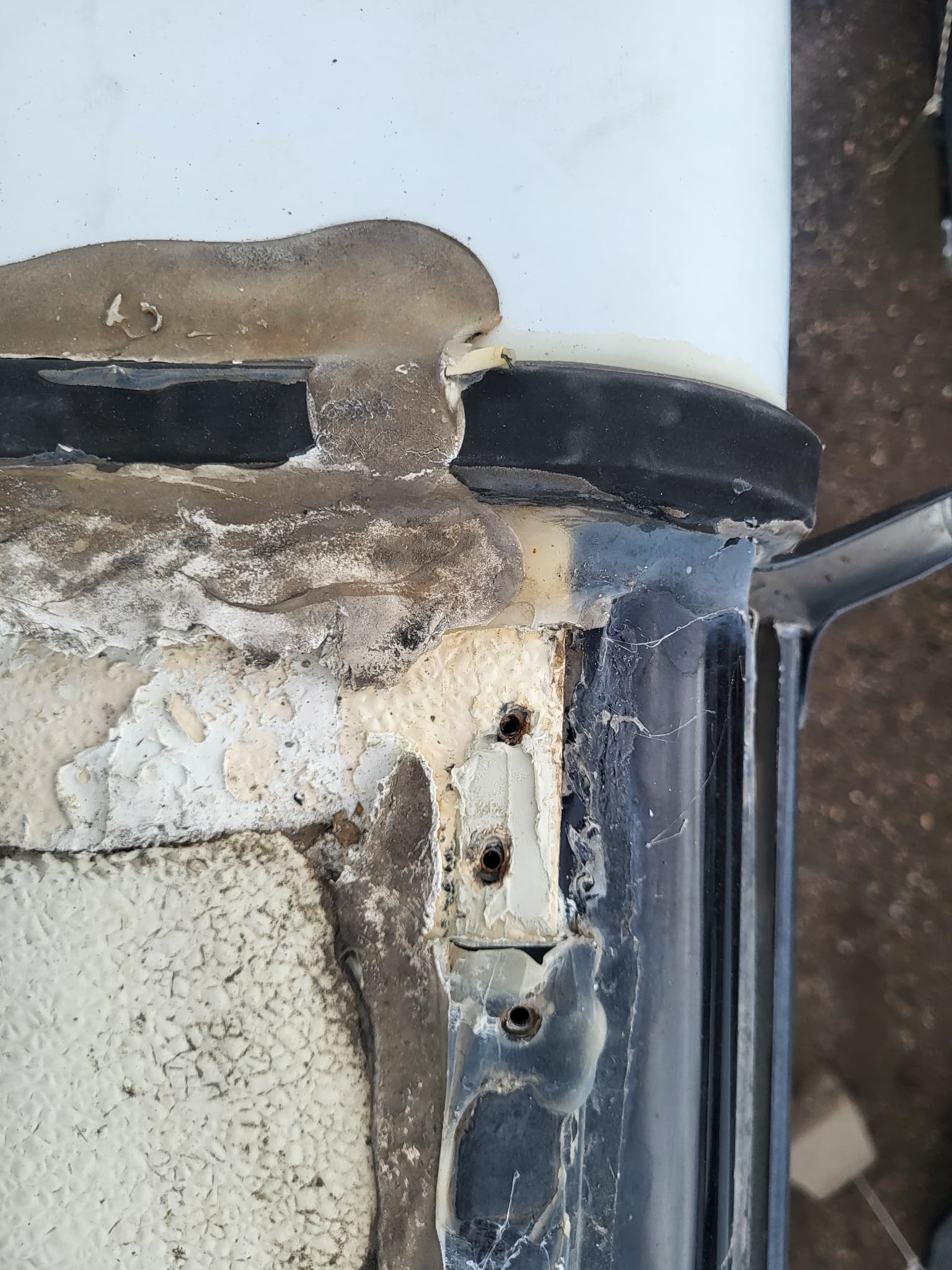 Damaged sealant on RV roof termination bar before repair