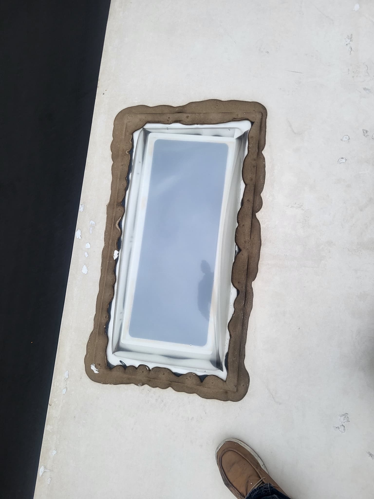 Old and dirty sealant around skylight on RV roof before replacement