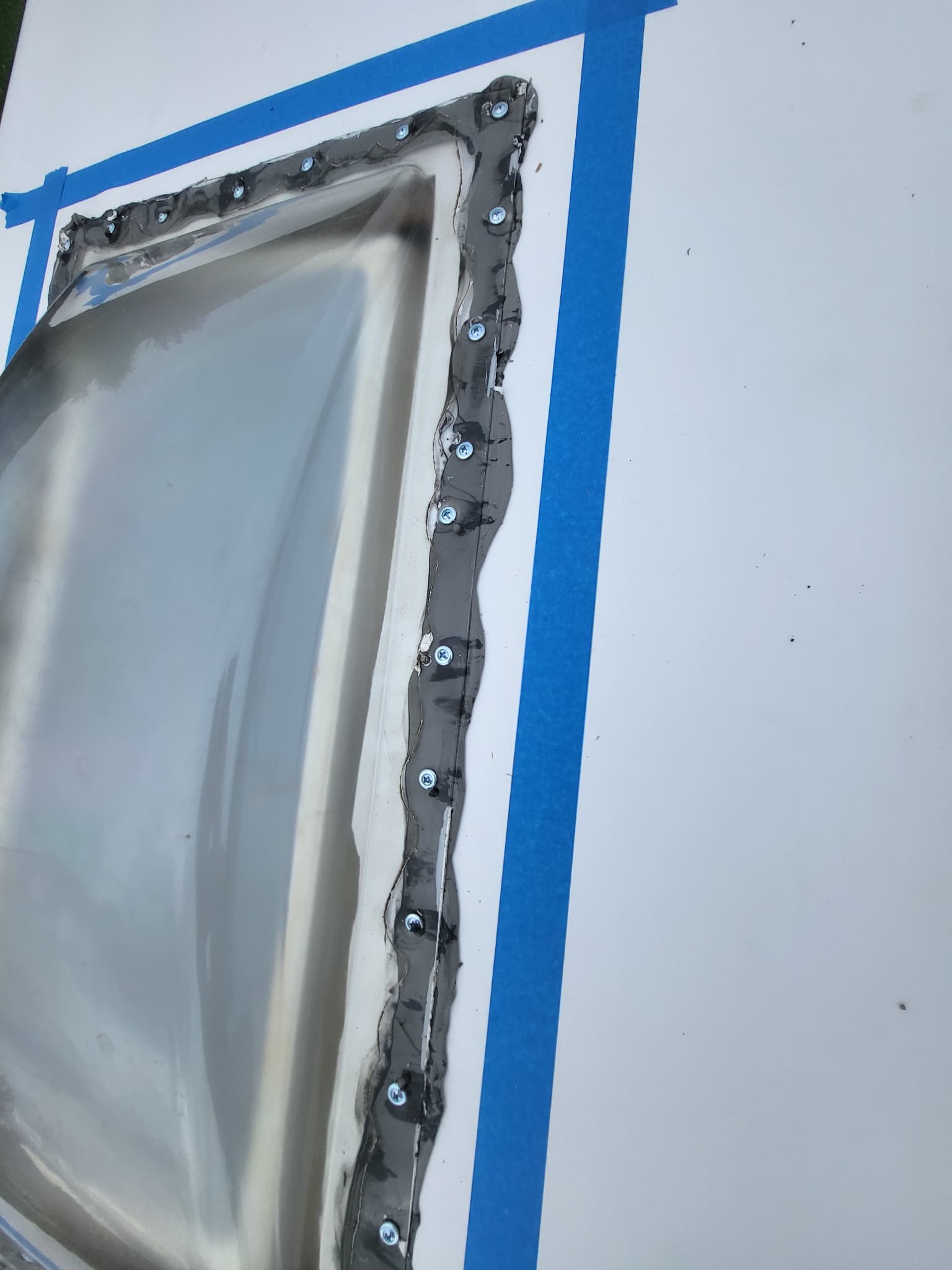 Skylight installed with masking tape on RV roof before sealing