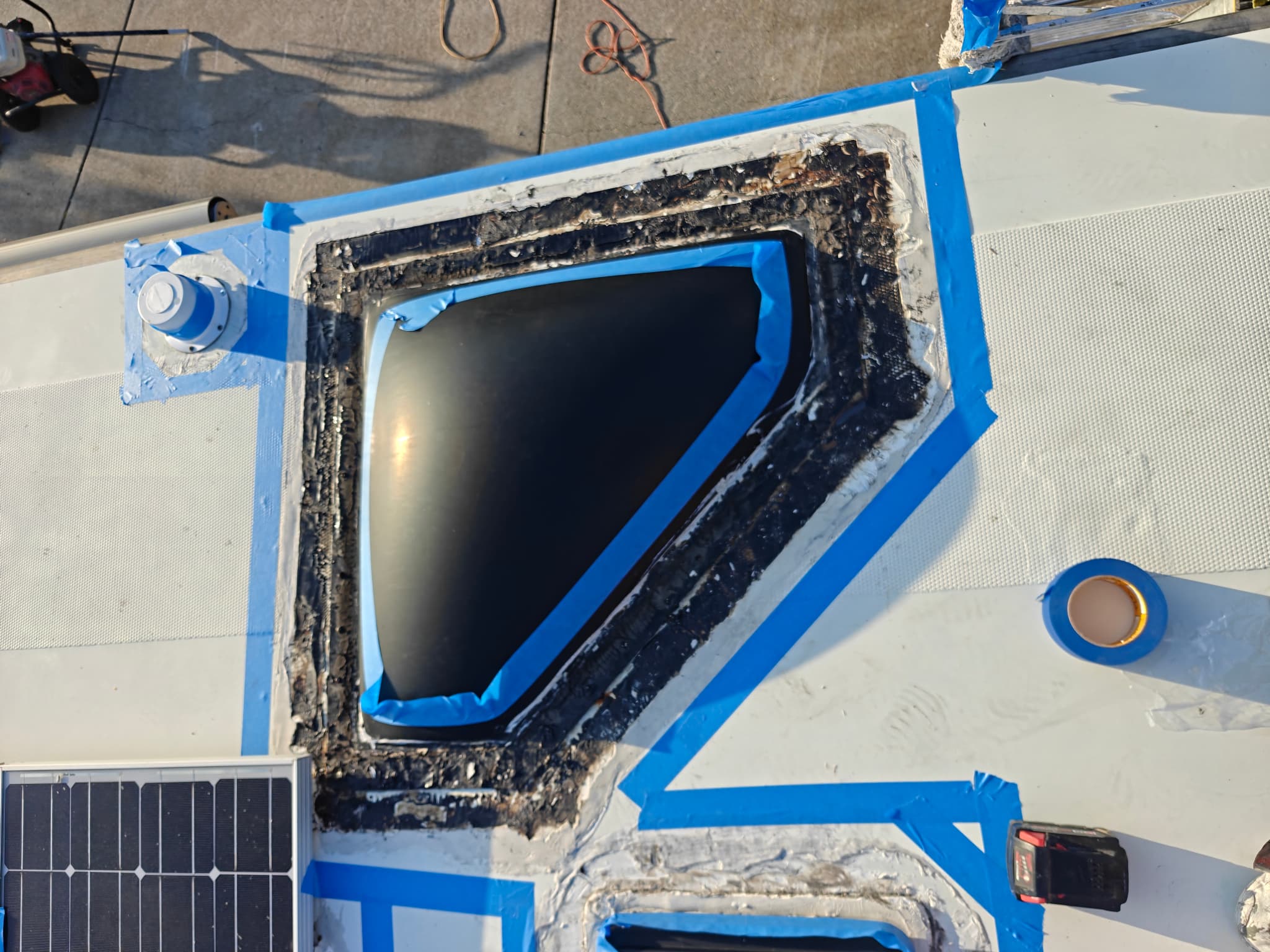 Skylight preparation with sealant removal and masking tape on RV roof
