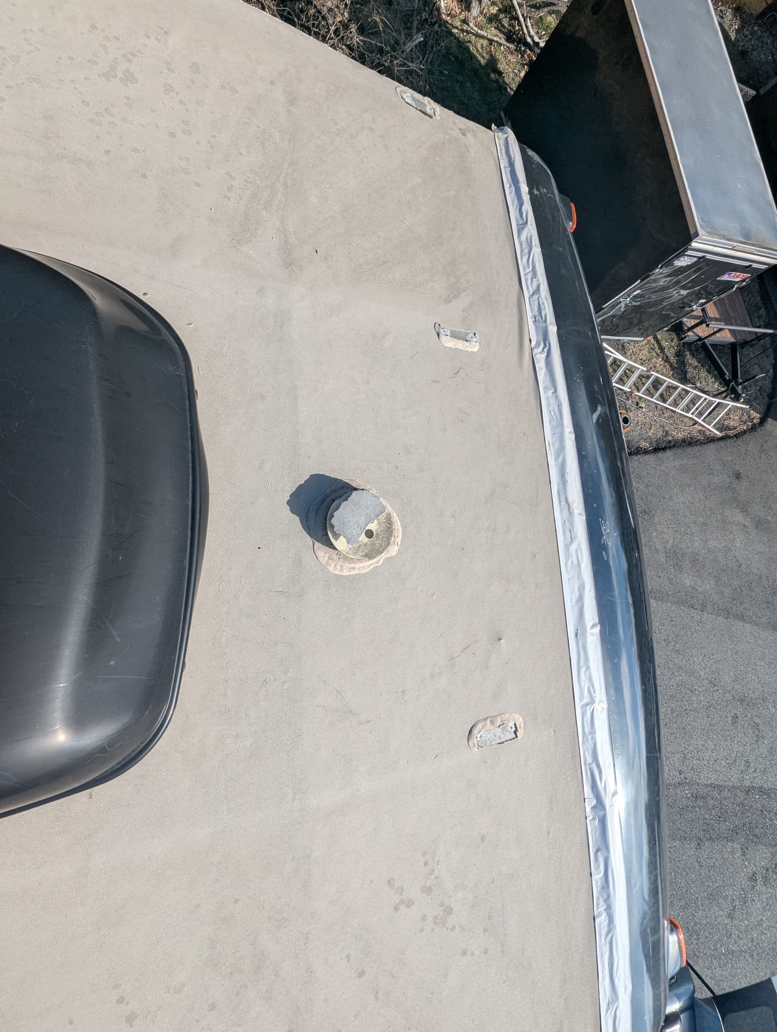 Broken plumbing vent and taped front cap showing failed RV roof repair