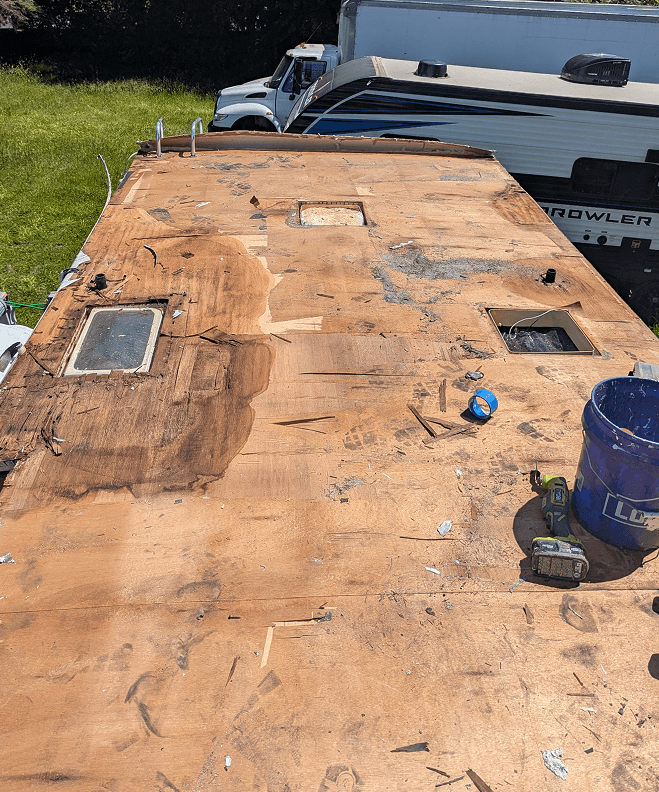 Wet and deteriorated roof decking exposed after membrane removal on RV roof